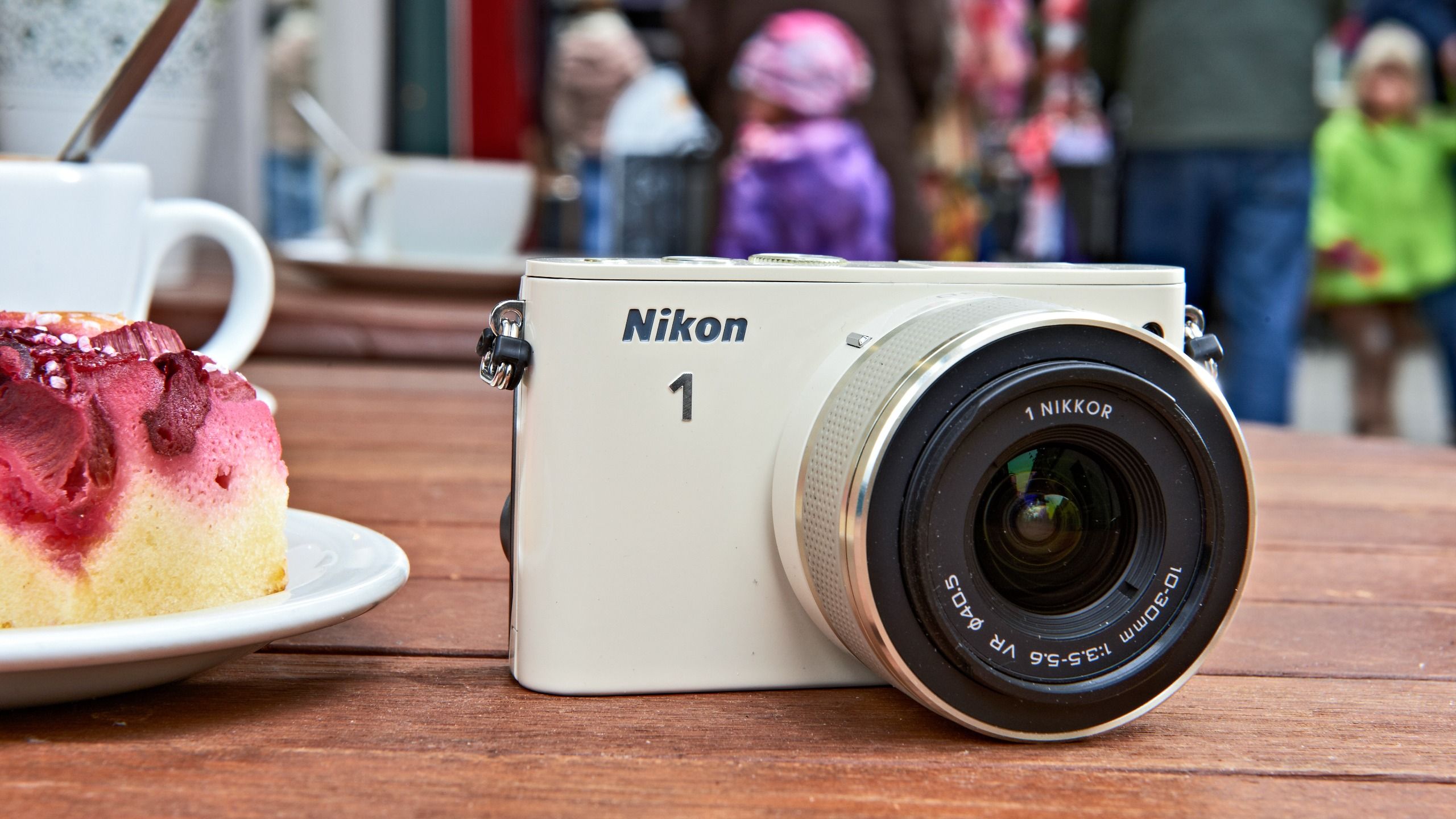 A compact Nikon 1 mirrorless camera held in one hand